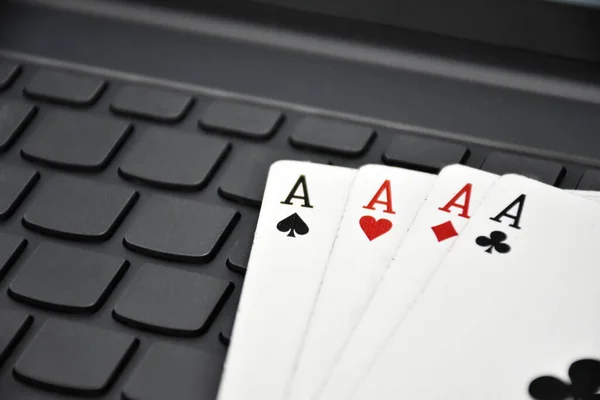 Poker paper cards on blank laptop keyboard, soft and selective focus, concept for playing cards online with other people at home and recreational activity.