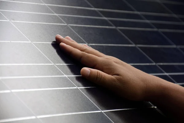 Closeup hand on photovoltaic or solar cell panel, soft and selective focus on hand, self photovoltaic panel checking by touch the surface, sustainable energy in human life concept.