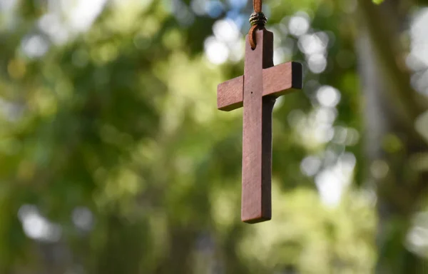 Wooden cross hanging on tree branch, soft and selective focus, natural bokeh tree background, concept for hope, love, forgiveness and belief in Jesus around the world.