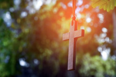 Ağaç dalında asılı ahşap haç, yumuşak ve seçici odak, doğal bokeh ağacı arka planı, umut, sevgi, bağışlama ve dünya çapında İsa 'ya inanç kavramı..