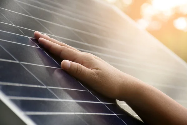 Fotovoltaik ya da güneş pili paneline yakın el, eldeki yumuşak ve seçici odaklanma, yüzeye dokunarak kendini kontrol eden fotovoltaik panel, insan yaşam konseptinde sürdürülebilir enerji.