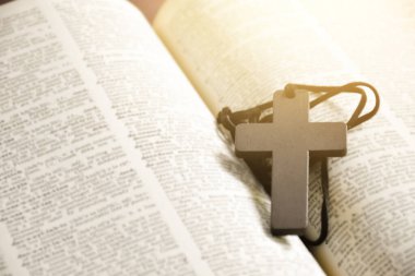 İngilizce dilbilgisi kitabının ortasında kahverengi ahşap haç var. Yumuşak ve seçici odaklı..