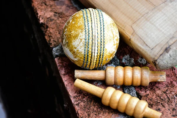 Old and unused cricket sport equipments on brick, bat, wicket, old leather ball, soft and selective focus.