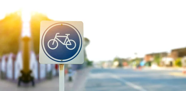 Bike path traffic sign on metal pole, soft and selective focus, blur main road background.