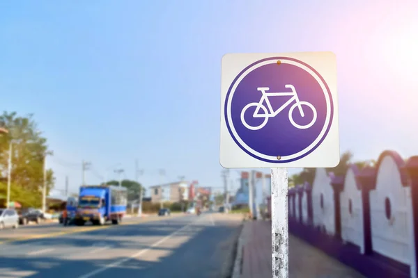 Bike path traffic sign on metal pole, soft and selective focus, blur main road background.