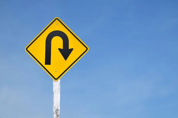 Traffic sign: Right U-turn sign on cement pole beside the rural road with white cloudy bluesky background, copy space.