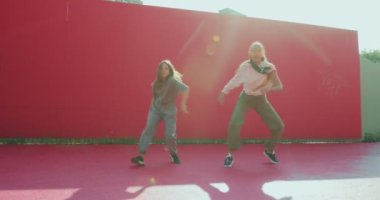 Modern bayan dansçılar, gün ışığında sokakta dans ederek dans ederler. Şık kızlar enerjik danslar yaparlar.