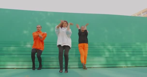 Танцевальная команда, стильные танцоры показывают современный огненный провокационный танец на зеленом фоне снаружи — стоковое видео