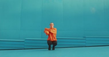 Dans eden, topuklu ayakkabı giyen homoseksüel bir adam, açık havada, mavi duvarın yanında vogue femme dansı yapıyor. Cinsiyet ve sanat konsepti