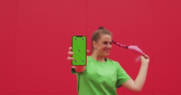 Sorrindo menina feliz mostrando telefone com tela verde chave chroma com pontos de rastreamento, se divertindo. Publicidade vídeo — Vídeo de Stock