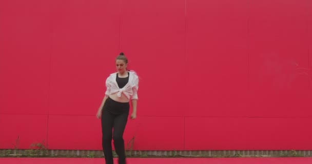 Moderna chica de 20 años bailando divirtiéndose, sonriendo sobre fondo rojo afuera. Música, concepto de danza contemporánea — Vídeos de Stock