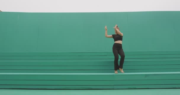 Dans eden genç kız dışarıda enerjik ve anlamlı bir modern dans sergiliyor. Dansçı kadın yeşil zeminde hareket ediyor. — Stok video