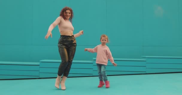 ダンスのお母さん、小さな女の子の子供の娘は青い壁で外でダンスをします。二代目。幸せな母親 — ストック動画
