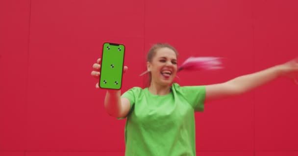 Radostná moderní mladá dívka ukazuje telefon s barevným klíčem zelené obrazovce se sledovacími body, baví. Reklamní video — Stock video