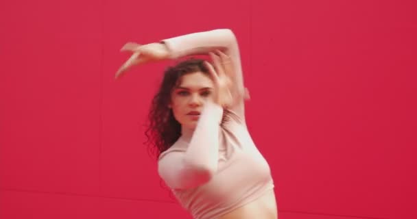 예쁜우아 한 춤을 추는 소녀가 빨간 벽에 대해 열정적으로 섹시 한 춤을 추고 있습니다. 전문 무용수인 소녀는 손을 멋있게 움직 인다 — 비디오