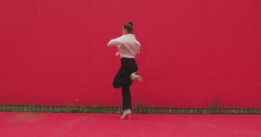Dans eden mutlu genç kız dışarıda enerjik bir dans sergiliyor. Modern kadın dansçı Red Street Duvarı 'na yaslanıyor