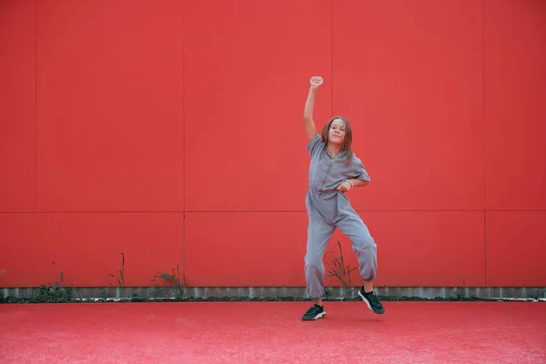 Enerjik dansçı genç kız kırmızı arka planda yumruğunu kaldırdı. Harika bir dansçı hip hop dansı yapar. — Stok fotoğraf