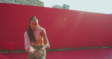 Dans eden melez genç kız dışarıda güneş ışığında enerjik ateşli Afrikalı dansı yapıyor. Kadın dansçı etkileyici.