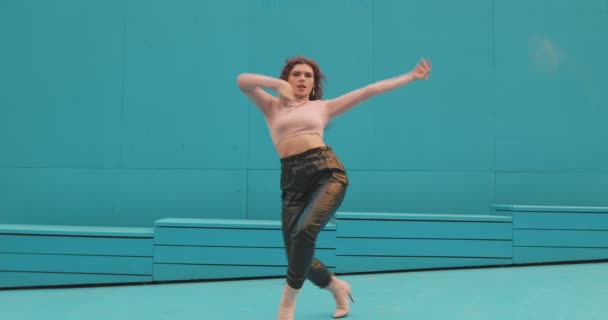 Tanzende Mädchen führen leidenschaftlichen Ausdruckstanz im Freien auf blauem Hintergrund auf. Anmutige Tänzerin bewegt sich cool — Stockvideo
