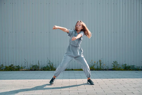 Kentin arka planında hip hop dansı yapan şık bir genç kız. Breakdance hareketleri yapan enerjik dansçı. — Stok fotoğraf