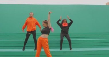 Dans eden insanlar, havalı dansçılar dışarıda yeşil arka planda çağdaş dans ediyorlar. Müzik klibi için reklam videosu