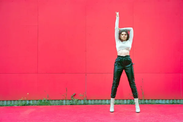 Cool уверенно молодая сексуальная девушка стоит с поднятой рукой за красной стеной с копировальным пространством. Феминизм, понятие прав женщин — стоковое фото