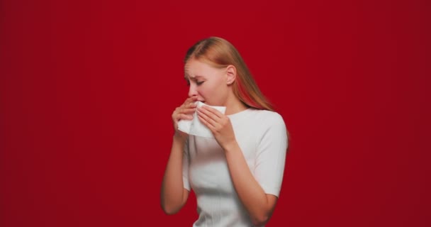 Menina alérgica insalubre pegou frio espirrando no guardanapo sentindo-se mal, sofrendo de gripe no fundo estúdio vermelho — Vídeo de Stock