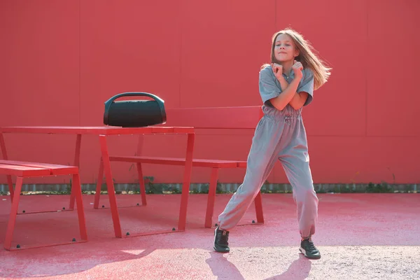 Крутая девушка-подросток, танцующая на улице, слушает музыку с открытым портативным динамиком на солнце. Реклама танцевальной школы — стоковое фото