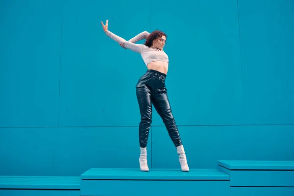 Elegante chica sexy joven modelo femenino posando al aire libre por la pared azul con espacio de copia para el anuncio. Mujer estilo de vida urbano —  Fotos de Stock