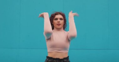 Dans eden kadın, mavi arka planda çağdaş anlamlı bir dans sergiliyor. Profesyonel dansçı kız.