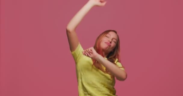 Neşeli genç dansçı kız başarıyı kutluyor enerjik müziğin tadını çıkarıyor pembe stüdyo arka planında tuhaf bir dans gösterisi yapıyor. — Stok video