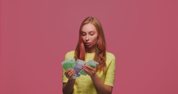 Éxito financiero. Feliz chica rica contando dinero, pensando cómo gastar dinero en efectivo en fondo de estudio rosa — Vídeos de Stock