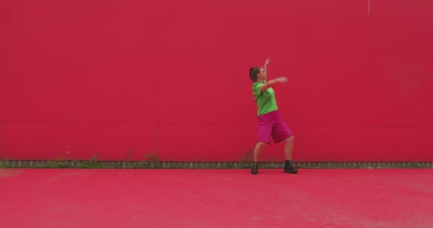 Dancing young happy girl perform energetic expressive dance against red wall. Modern joyful female dancer cool moving — Stock Video