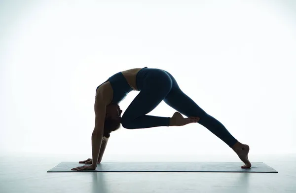 体形健美的女运动员反复练习瑜伽，阿萨那对着狗做姿势，膝头对鼻子。健康生活方式概念 — 图库照片