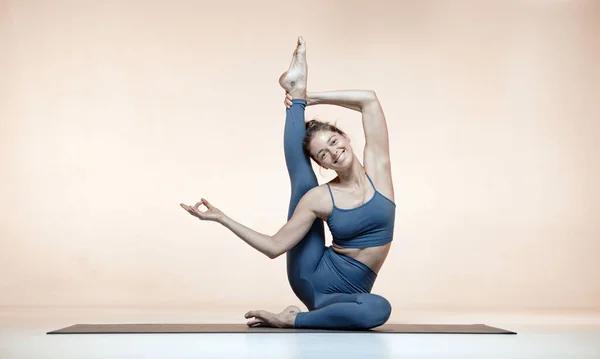 微笑瑜伽女练习瑜伽米色工作室背景与版权空间的广告。普拉提和女人的健康 — 图库照片