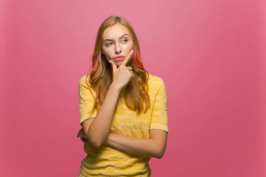 Genç kız kaşlarını kaldırdı çene planı düşündü, pembe stüdyo arka planı üzerinde düşündü.