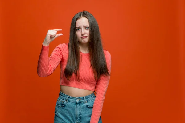 Dissapointed ung flicka visar liten storlek eller liten bit gest med fingrar, låg rating på orange bakgrund — Stockfoto