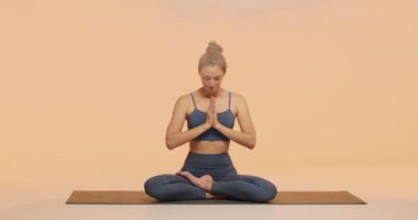 Genç kız koltuğu yoga stüdyosunda kauçuk minderde bağdaş kurarak lotus asana alıştırması yapıyor. Stres yok, sağlıklı yaşam tarzı kavramı