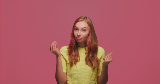 Young girl showing money pay me gesture, asking fee, reward, debt or donation on pink background. Female need funds — Stock Video