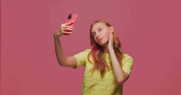 かなり若い女の子は携帯電話で自撮りします。美しい女性モデルの笑顔ポージングは、ソーシャルネットワークのための写真を作る, blog — ストック動画