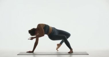 Esnek, formda, genç bir kız yoga ya da pilates yapıyor. Beyaz arka planda esneme ve iyileşme için Vahşi Şey Pozu veriyor.