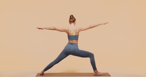 Allenamento di yoga. Vista posteriore di giovane donna istruttrice di fitness che fa pacifico Warrior Pose. Cura del corpo e della mente concetto — Video Stock