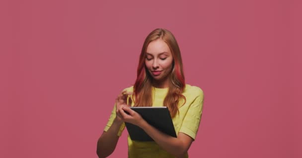 Mujer joven creativa pensativa con tableta, pensando, planeando hacer lista, sueño, crear idea en fondo de estudio rosa — Vídeos de Stock