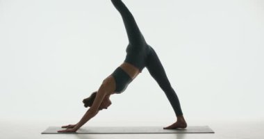 Yoga dersi videosu. Kadın fitness eğitmeni zarif bir performans sergiliyor. Beyaz stüdyo arka planında Vahşi Şey Poz Camatkarasana.