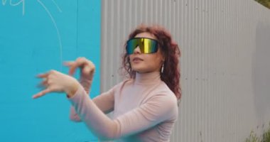 Güneş gözlüklü dansçı moda kızı dışarıda dans ediyor. Kadın dansçı. Havalı hareketli eller.