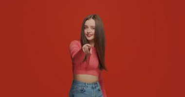 Gel buraya. Güzel bir genç kız elleriyle işaret ediyor, yaklaşmaya davet ediyor, turuncu stüdyo geçmişinde flört ediyor.