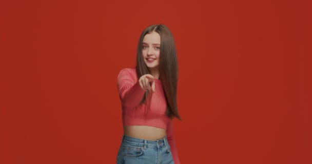Come here gesture. Beautiful young girl beckoning with hands, inviting to approach, flirting on orange studio background — Stock Video