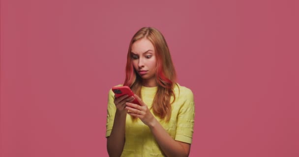 Modernes junges Mädchen, das die App des sozialen Netzwerks auf dem Handy nutzt, schockiert von den Inhalten und schaut erstaunt in die Kamera. — Stockvideo