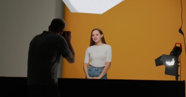 Nos bastidores, atrás de um tiro. Modelo feminino profissional posar na sessão fotográfica para fotógrafo criação de fotografia publicitária — Vídeo de Stock