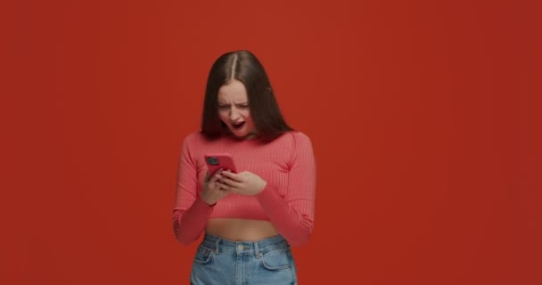 Överraskad flicka ser telefon med förvåning, fick chockerande nyheter eller innehåll i sociala nätverk — Stockvideo